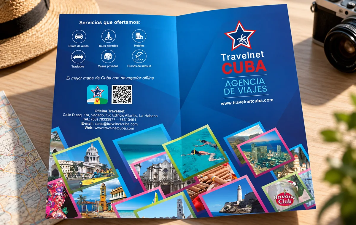 Travelnet Cuba brochure lying open on a desk, in deep blue: a grid of services with icons, an app QR code, and a collage of tilted Cuba photographs along the foot